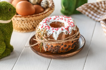 Plate with tasty Easter cake and beautiful gypsophila flowers tied by string on white wooden table