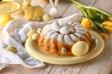 Plate with tasty Easter cake and painted eggs on white wooden table