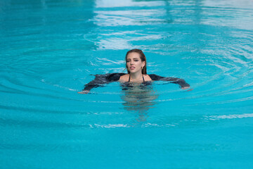 Fashion woman in luxury pool. Elegant sexy woman in the white bikini on tanned slim body posing near swimming pool. Rich summer rest.
