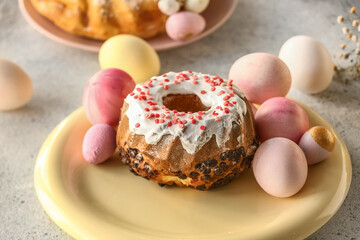 Plate with tasty Easter cake and painted eggs on grey table