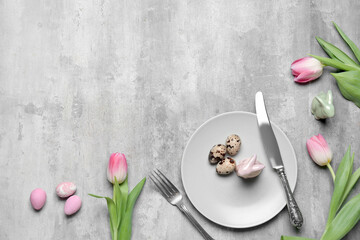 Table setting with Easter eggs and tulips on grunge background