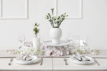 Beautiful table setting for International Women's Day celebration with eustoma and orchid flowers in light room