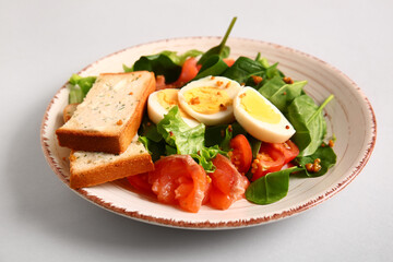 Fototapeta na wymiar Plate of delicious salad with boiled eggs and salmon on grey background