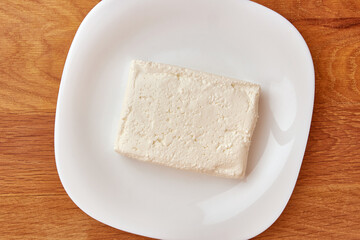 A slice of sour milk cheese on a white plate.