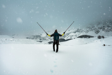 Hiker with backpack stand on rock in in heavy snowstorm. Winter on mountain Lebrsnik.