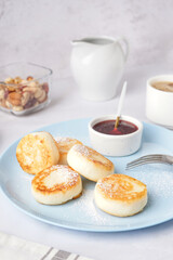 Plate with tasty cottage cheese pancakes and strawberry jam on light background, closeup