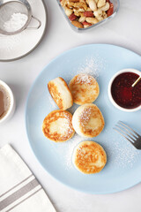 Plate with tasty cottage cheese pancakes and strawberry jam on light background, closeup