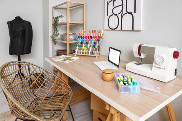 Interior of modern atelier with tailor's workplace, shelving unit and mannequin