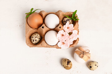 Fototapeta na wymiar Easter eggs and sakura flowers on white wooden background