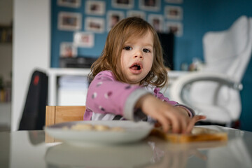 one girl small caucasian toddler female child eat at the table at home