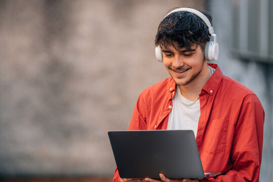 young man on the street with headphones and laptop