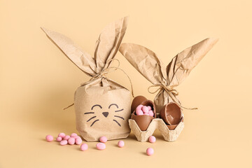 Easter bunny gift bag, holder with chocolate eggs and candies on beige background