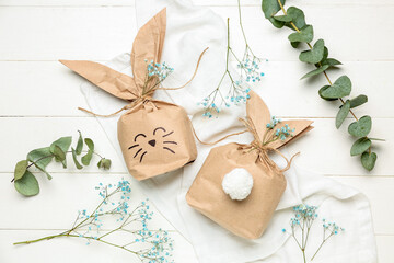 Fototapeta na wymiar Composition with Easter bunny gift bags, gypsophila flowers and eucalyptus branches on white wooden background