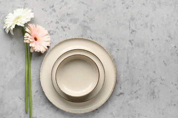 Table setting with beautiful gerbera flowers on grey grunge background