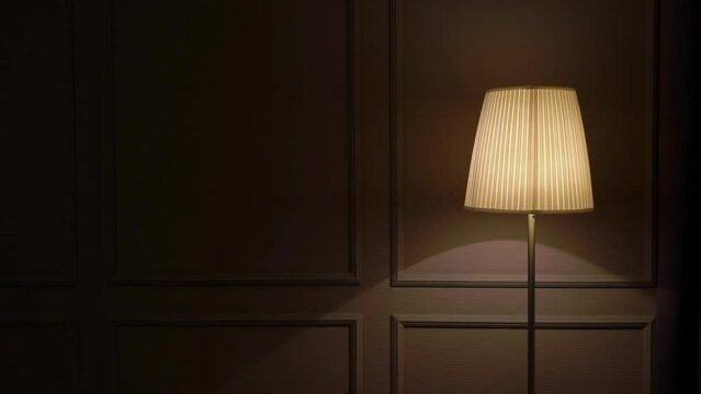 Lampshade lamp, floor lamp on the background of the wall. Interior in the evening or at night. Warm light at home.