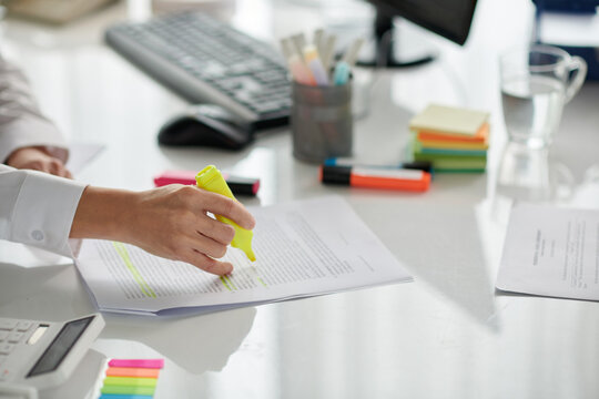 Hands of clerk highlighting part of document with yellow color