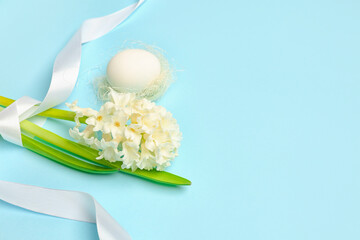 Beautiful hyacinth flower, Easter egg and ribbon on blue background