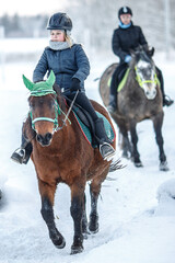 A girl rides a horse in the snow and frost of the cold north