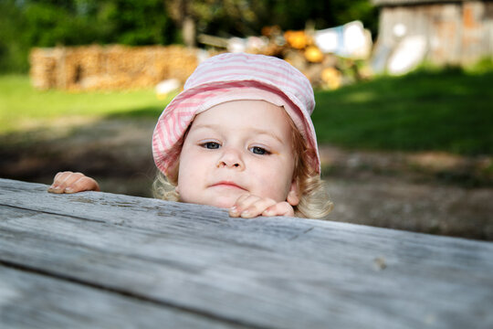 A little girl sits on an old railroad track on a warm summer morning