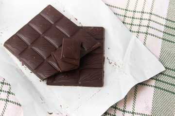 A chopped dark chocolate bar on the paper that wraps it