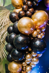 Background, texture of round black, golden, colored balloons on the photo zone against the wall in the interior. Close-up photography, holiday, birthday, wedding.