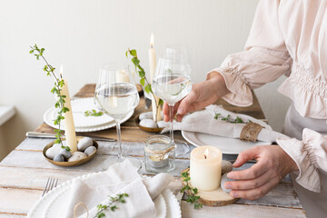 Rustic zero waste wedding decor with natural elements. Wooden table, candles, linen napkins, branches with green leaves. Eco-friendly decoration for the special dinner. Romantic and cozy place