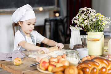 Cute little girl baking homemade sweet pie together, having fun. Home bakery, little kids in process of food preparation in the kitchen at home, helping mother, doing chores. Mother's or Women's day