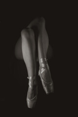 Legs with ballet shoes on a black background