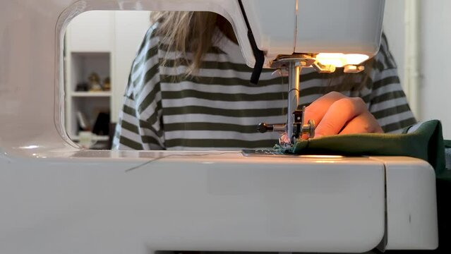 Close-up sewing proccess on sewing machine. Side view needle work. Handmade cloth, making handcrafted from green velveteen fabric, hand-sewn dress. video from back of machine. manufacturing business