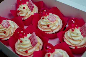Six birthday cupcakes in a box. Cute decoration. White pies with curd cream, pink chocolate and lollipops. For a girls party.