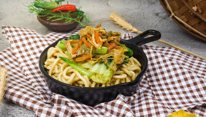 Indonesian famous street food, mie ayam, noodles with chicken. Served in frying pan. Selective focus