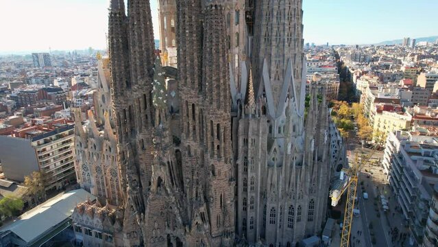 Barcelona, Spain - 12.08.2021: Panoramic aerial view of Eixample residential district and famous Sagrada Familia Cathedral temple with city with multiple residential buildings in background. 4K.