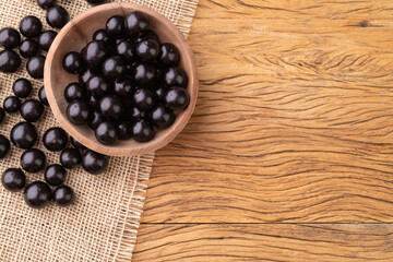 Jabuticabas on a bowl over wooden table with copy space