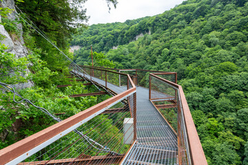 Okatse Canyon in Georgia with hanging metal pedestrian pathway trail above deep precipice, lush...