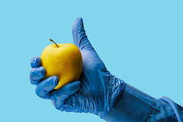 An apple in the doctor's hand. Background, selective focus. Isolated blue medical backdrop