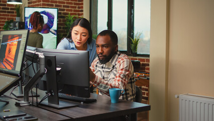 Creative agency employees using computers to develop new graphics interface in office, doing...