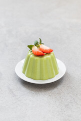 Spinach cream pudding, Panna Cotta with strawberries, on a plate. Light grey background