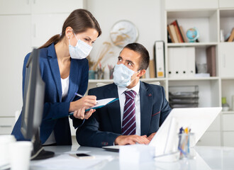 Director in protective medical mask gives instructions to secretary in office