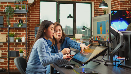 Female content creators editing professional images with retouching software and stylus pen,...