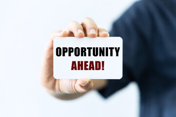 Opportunity ahead text on blank business card being held by a woman's hand with blurred background. Business concept to inform audience that there is new opportunity waiting.