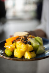 Servant holding a plate with fresh fruits in hawaii in a cafe