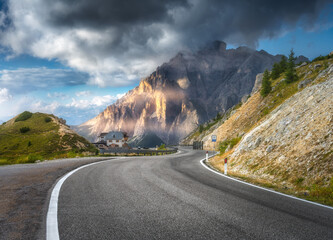 Mountain road at sunny day in summer. Dolomites, Italy. Beautiful roadway, green tress, high rocks...