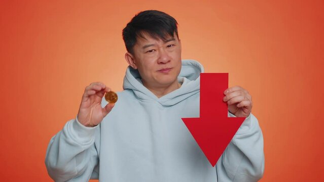 Asian man show golden bitcoins indicating red arrow banner down sign, decrease of exchange rate. Unsuccessful bankruptcy business, fall of stock cryptocurrency market investment mining BTC technology