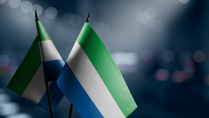 Small flags of the Sierra Leone on an abstract blurry background - obrazy, fototapety, plakaty