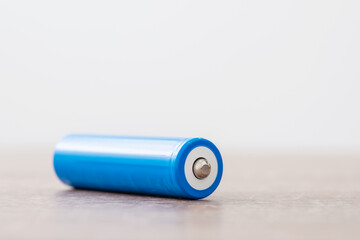 Lithium battery on wooden table. 18650 type battery with positive clamp facing the camera