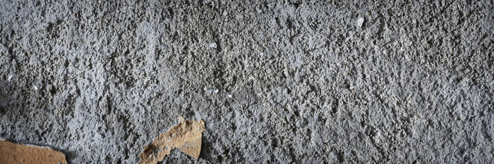 Peeling paint on the wall. Panorama of a concrete wall with old cracked flaking paint. Weathered rough painted surface with patterns of cracks and peeling. Wide panoramic grungy texture for background