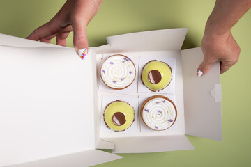 female hands open a box with different cakes dessert home delivery