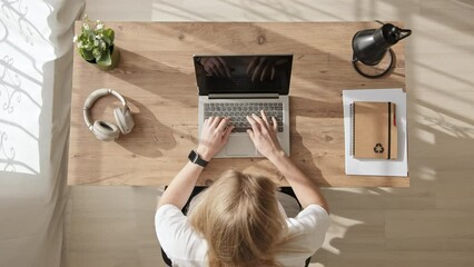 Top down view of blonde girl who has finished working, closes her laptop, picks it up from table and walks out of frame. freelancer woman or office worker ends work day and leaves.