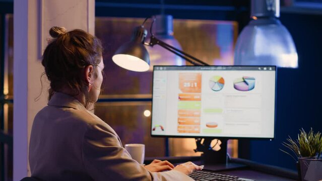 Office worker looking at computer running diagrams on screen, planning economy graphs late at night. Female entrepreneur typing data to create business report, analyzing investment at desk.