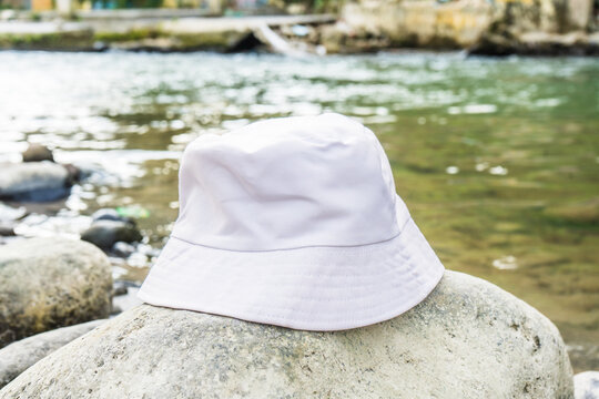 With its pristine white color and tasteful placement above a rock, this bucket hat enhances the overall aesthetic of the tranquil river setting